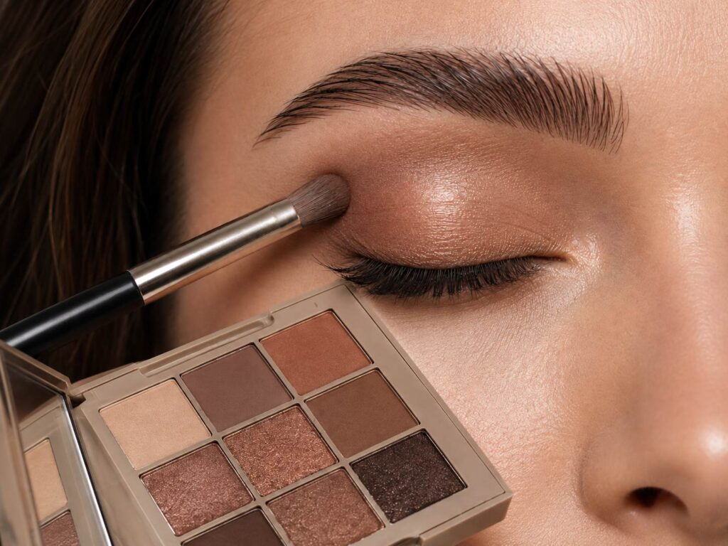 User applying warm-toned eyeshadow from a custom palette